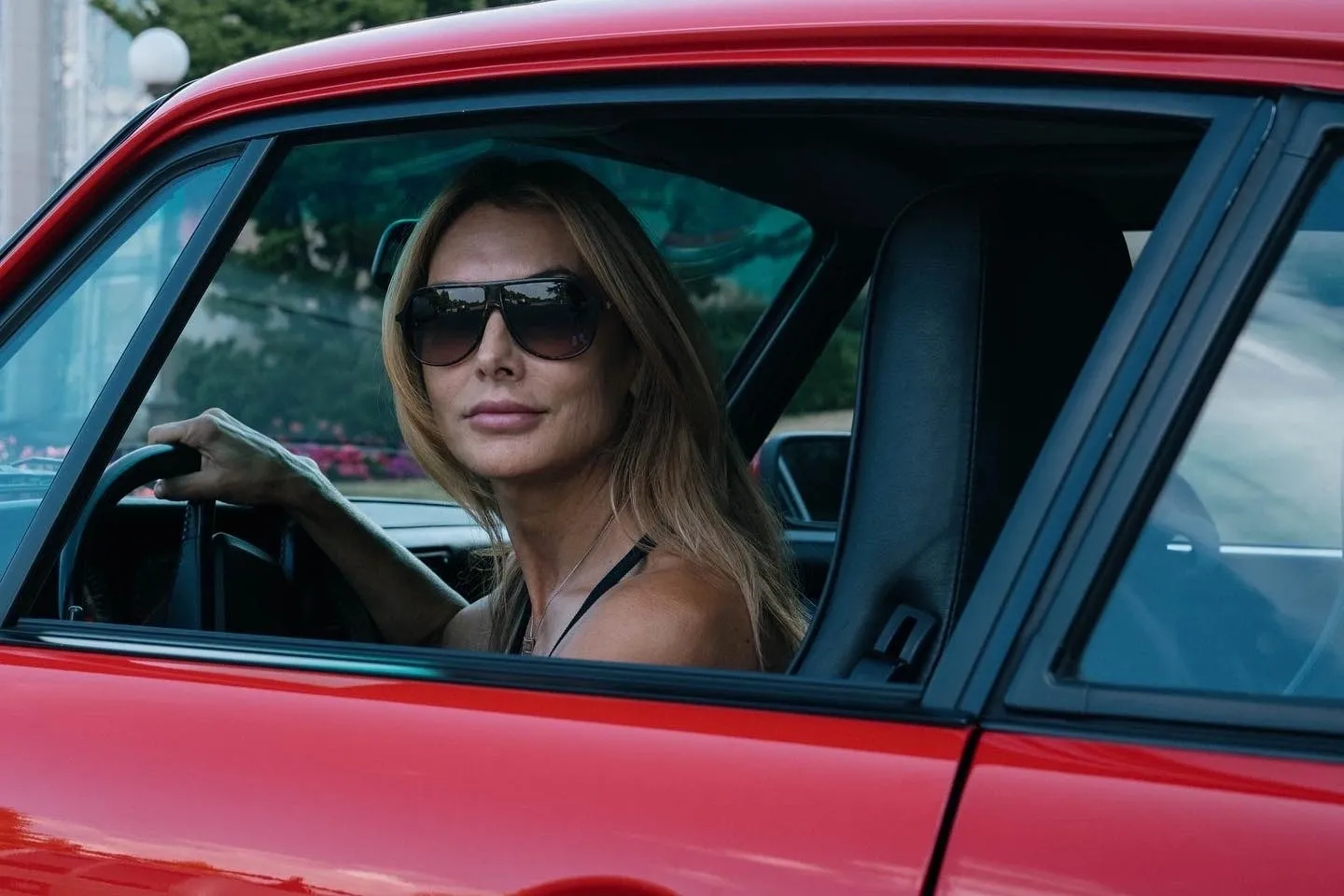 A woman sitting in the driver 's seat of a red car.