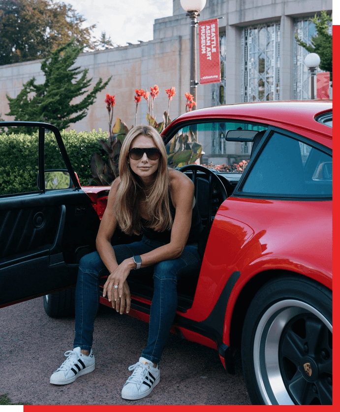 A woman sitting in the back of a red car.