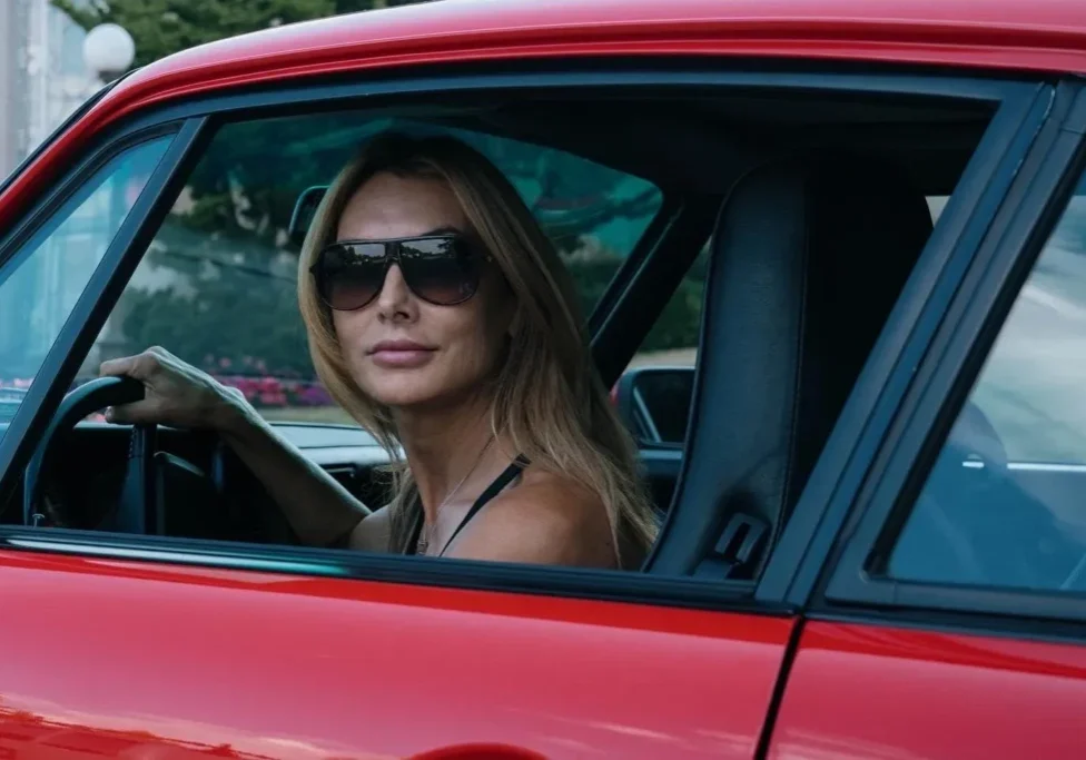 A woman sitting in the driver 's seat of a red car.